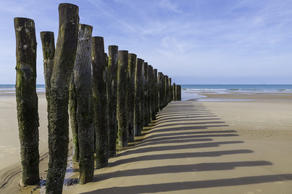 beach in france with wooden poles and the channel between france and england