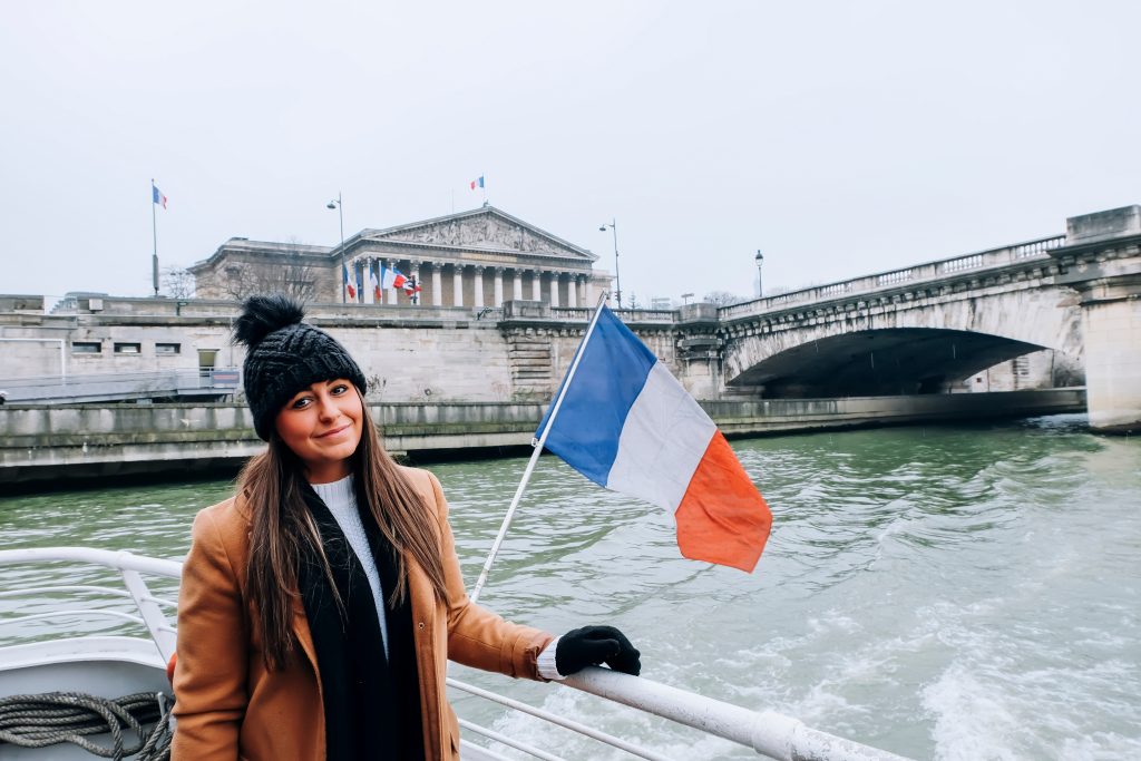 Woman in winter clothing on a boat in Paris France with French flag